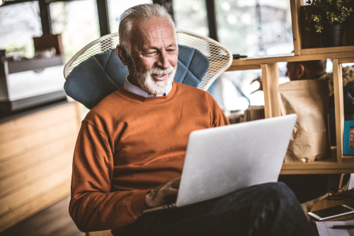 Old man sitting on chair on laptop