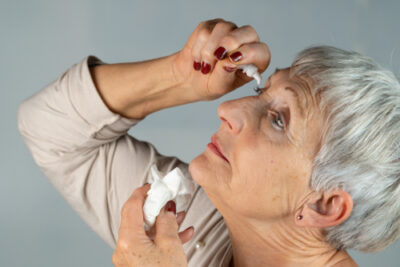 older woman using eyedrops