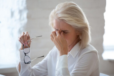 Woman rubbing her eyes while holding glasses